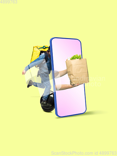 Image of Handsome delivery man giving order right from smartphone\'s screen, fast delivery concept