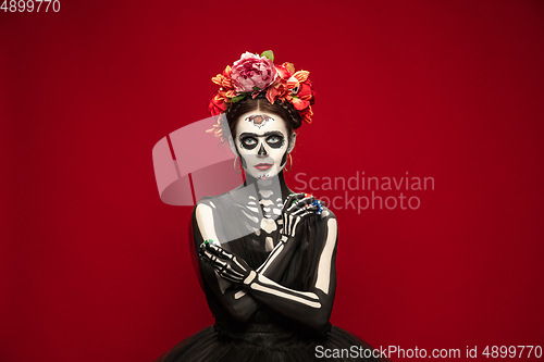 Image of Young girl in the image of Santa Muerte, Saint death or Sugar skull with bright make-up. Portrait isolated on studio background.