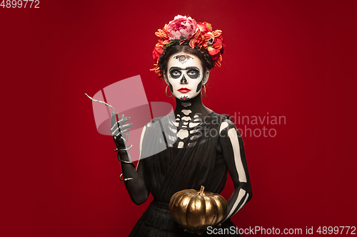 Image of Young girl in the image of Santa Muerte, Saint death or Sugar skull with bright make-up. Portrait isolated on studio background.