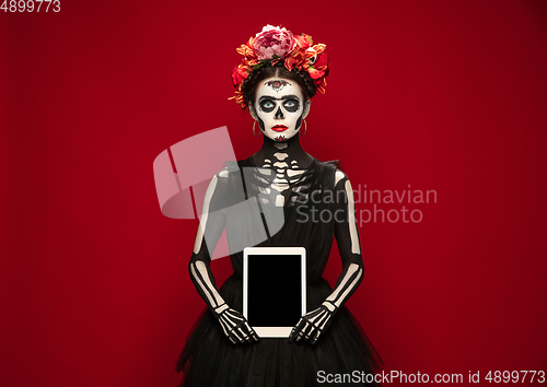 Image of Young girl in the image of Santa Muerte, Saint death or Sugar skull with bright make-up. Portrait isolated on studio background.