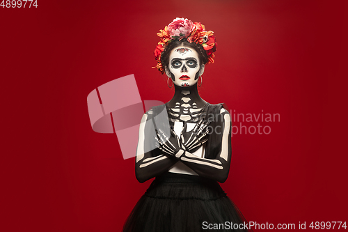 Image of Young girl in the image of Santa Muerte, Saint death or Sugar skull with bright make-up. Portrait isolated on studio background.