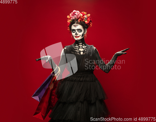 Image of Young girl in the image of Santa Muerte, Saint death or Sugar skull with bright make-up. Portrait isolated on studio background.