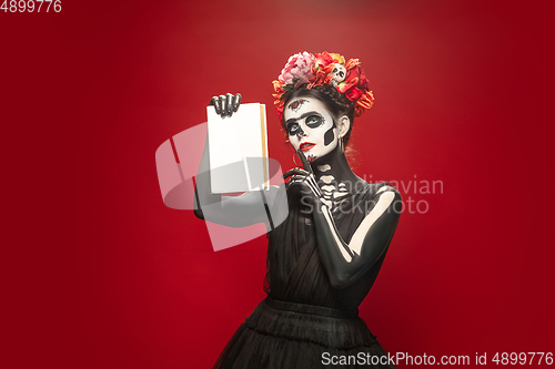 Image of Young girl in the image of Santa Muerte, Saint death or Sugar skull with bright make-up. Portrait isolated on studio background.