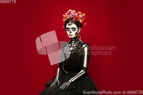 Image of Young girl in the image of Santa Muerte, Saint death or Sugar skull with bright make-up. Portrait isolated on studio background.