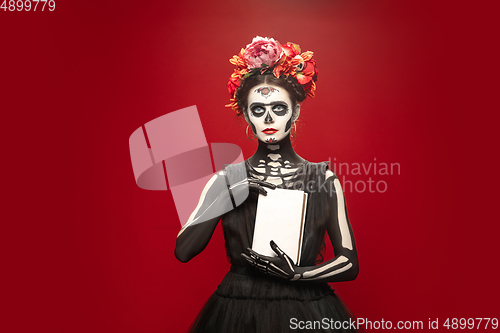 Image of Young girl in the image of Santa Muerte, Saint death or Sugar skull with bright make-up. Portrait isolated on studio background.