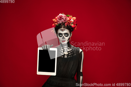 Image of Young girl in the image of Santa Muerte, Saint death or Sugar skull with bright make-up. Portrait isolated on studio background.