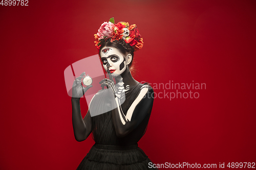 Image of Young girl in the image of Santa Muerte, Saint death or Sugar skull with bright make-up. Portrait isolated on studio background.