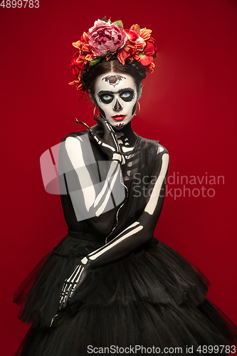 Image of Young girl in the image of Santa Muerte, Saint death or Sugar skull with bright make-up. Portrait isolated on studio background.