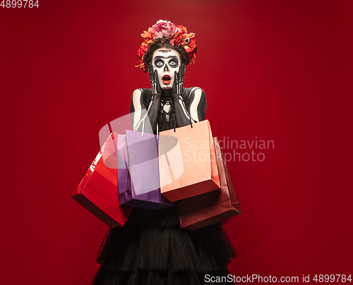 Image of Young girl in the image of Santa Muerte, Saint death or Sugar skull with bright make-up. Portrait isolated on studio background.