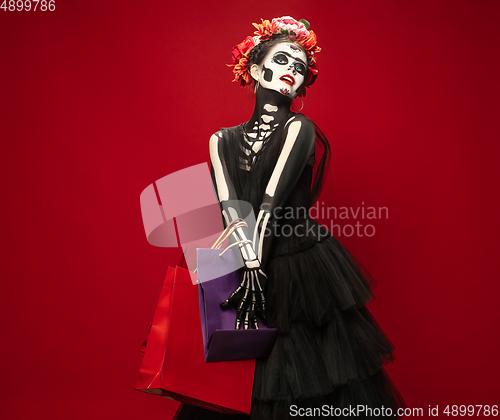 Image of Young girl in the image of Santa Muerte, Saint death or Sugar skull with bright make-up. Portrait isolated on studio background.