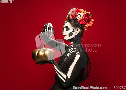 Image of Young girl in the image of Santa Muerte, Saint death or Sugar skull with bright make-up. Portrait isolated on studio background.