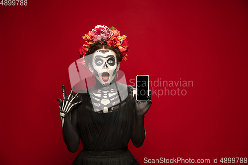 Image of Young girl in the image of Santa Muerte, Saint death or Sugar skull with bright make-up. Portrait isolated on studio background.