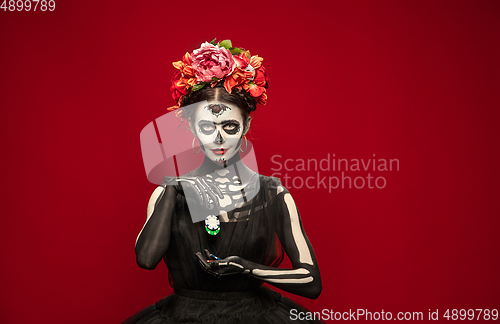 Image of Young girl in the image of Santa Muerte, Saint death or Sugar skull with bright make-up. Portrait isolated on studio background.