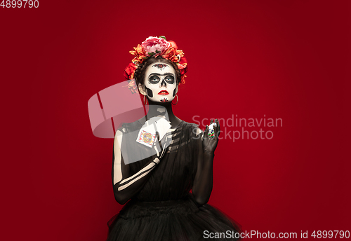 Image of Young girl in the image of Santa Muerte, Saint death or Sugar skull with bright make-up. Portrait isolated on studio background.