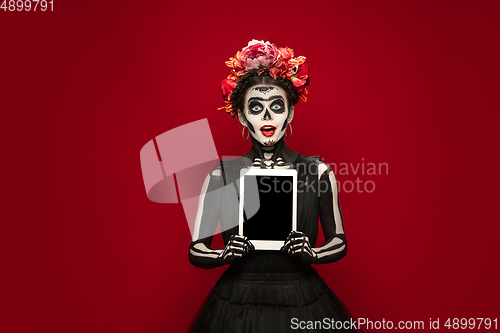 Image of Young girl in the image of Santa Muerte, Saint death or Sugar skull with bright make-up. Portrait isolated on studio background.