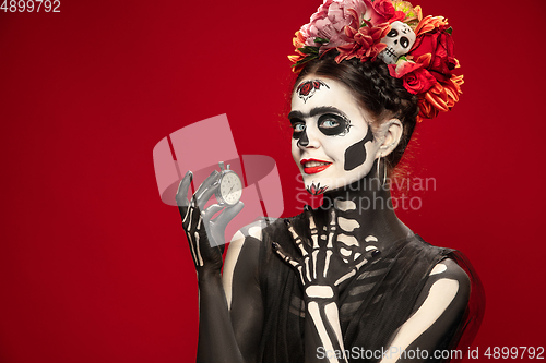 Image of Young girl in the image of Santa Muerte, Saint death or Sugar skull with bright make-up. Portrait isolated on studio background.