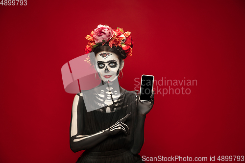 Image of Young girl in the image of Santa Muerte, Saint death or Sugar skull with bright make-up. Portrait isolated on studio background.