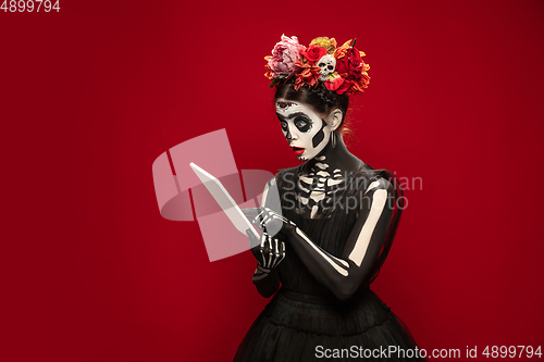 Image of Young girl in the image of Santa Muerte, Saint death or Sugar skull with bright make-up. Portrait isolated on studio background.