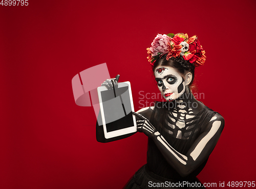 Image of Young girl in the image of Santa Muerte, Saint death or Sugar skull with bright make-up. Portrait isolated on studio background.