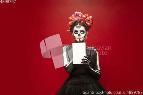 Image of Young girl in the image of Santa Muerte, Saint death or Sugar skull with bright make-up. Portrait isolated on studio background.