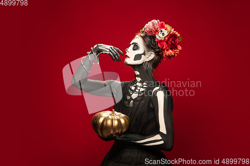 Image of Young girl in the image of Santa Muerte, Saint death or Sugar skull with bright make-up. Portrait isolated on studio background.