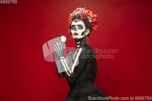 Image of Young girl in the image of Santa Muerte, Saint death or Sugar skull with bright make-up. Portrait isolated on studio background.