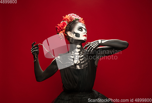 Image of Young girl in the image of Santa Muerte, Saint death or Sugar skull with bright make-up. Portrait isolated on studio background.