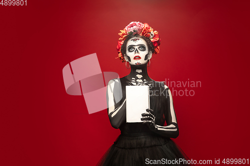 Image of Young girl in the image of Santa Muerte, Saint death or Sugar skull with bright make-up. Portrait isolated on studio background.