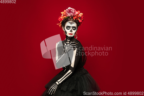 Image of Young girl in the image of Santa Muerte, Saint death or Sugar skull with bright make-up. Portrait isolated on studio background.