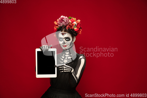 Image of Young girl in the image of Santa Muerte, Saint death or Sugar skull with bright make-up. Portrait isolated on studio background.