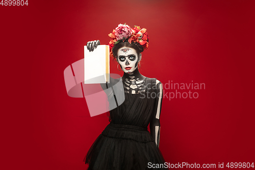 Image of Young girl in the image of Santa Muerte, Saint death or Sugar skull with bright make-up. Portrait isolated on studio background.