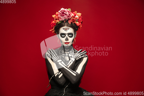 Image of Young girl in the image of Santa Muerte, Saint death or Sugar skull with bright make-up. Portrait isolated on studio background.