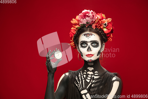 Image of Young girl in the image of Santa Muerte, Saint death or Sugar skull with bright make-up. Portrait isolated on studio background.