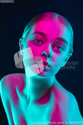 Image of Portrait of female fashion model in neon light on dark studio background.