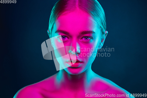 Image of Portrait of female fashion model in neon light on dark studio background.