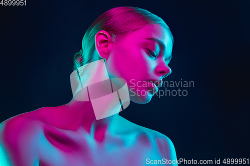 Image of Portrait of female fashion model in neon light on dark studio background.