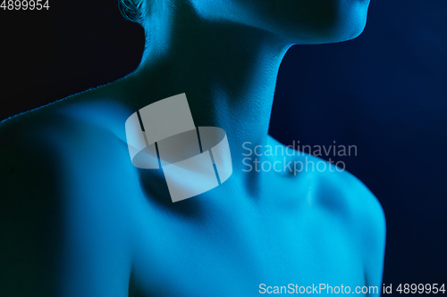 Image of Portrait of female fashion model in neon light on dark studio background.