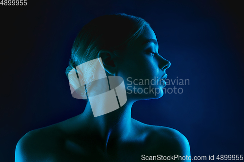 Image of Portrait of female fashion model in neon light on dark studio background.