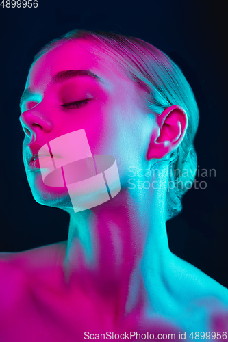 Image of Portrait of female fashion model in neon light on dark studio background.