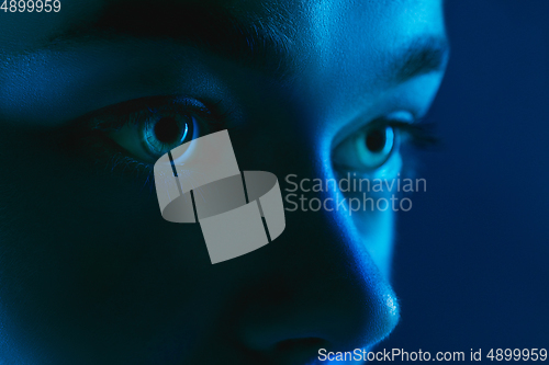 Image of Portrait of female fashion model in neon light on dark studio background.