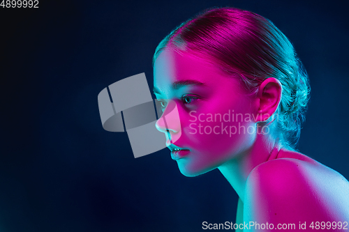 Image of Portrait of female fashion model in neon light on dark studio background.