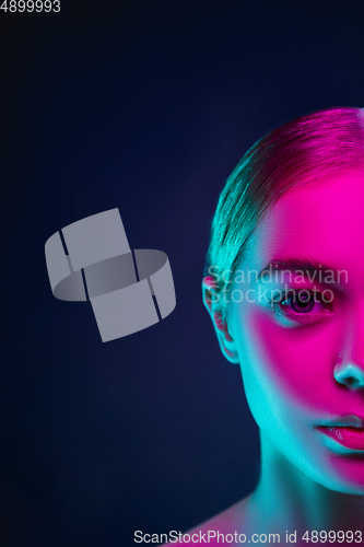 Image of Portrait of female fashion model in neon light on dark studio background.