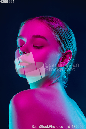 Image of Portrait of female fashion model in neon light on dark studio background.