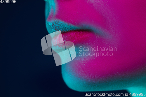 Image of Close up portrait of female fashion model in neon light on dark studio background.