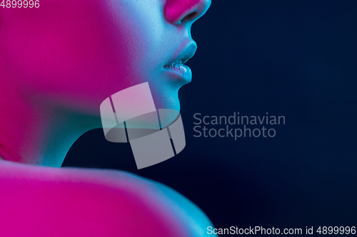 Image of Close up portrait of female fashion model in neon light on dark studio background.