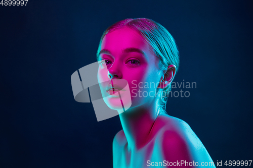 Image of Portrait of female fashion model in neon light on dark studio background.