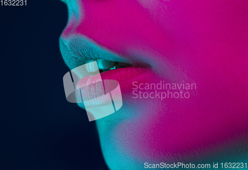 Image of Close up portrait of female fashion model in neon light on dark studio background.