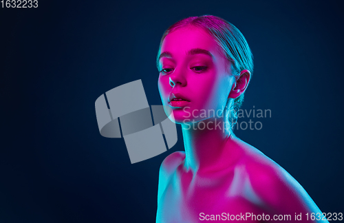Image of Portrait of female fashion model in neon light on dark studio background.