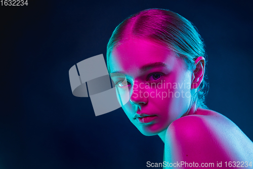 Image of Portrait of female fashion model in neon light on dark studio background.