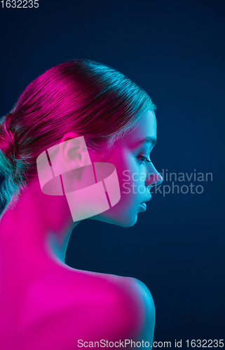 Image of Portrait of female fashion model in neon light on dark studio background.